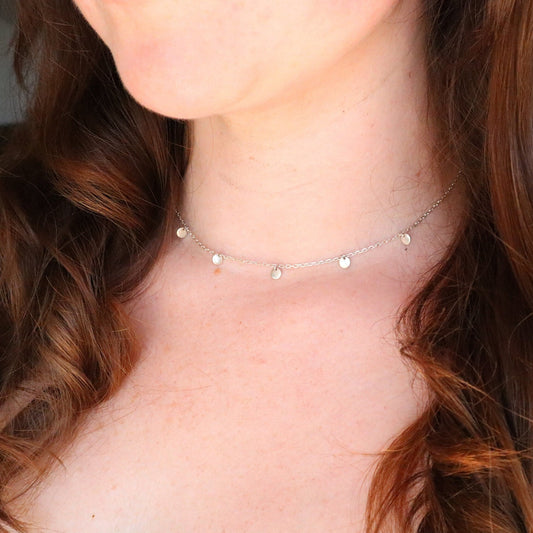 Satellite Drop Disc Choker displayed on a ladies neck. The Choker is sterling silver and has multiple discs spread around the necklace.