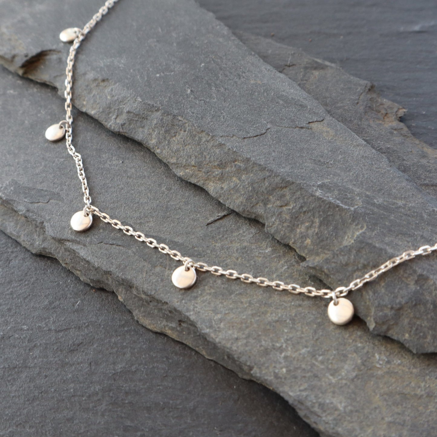 Satellite necklace displayed on a slate background.